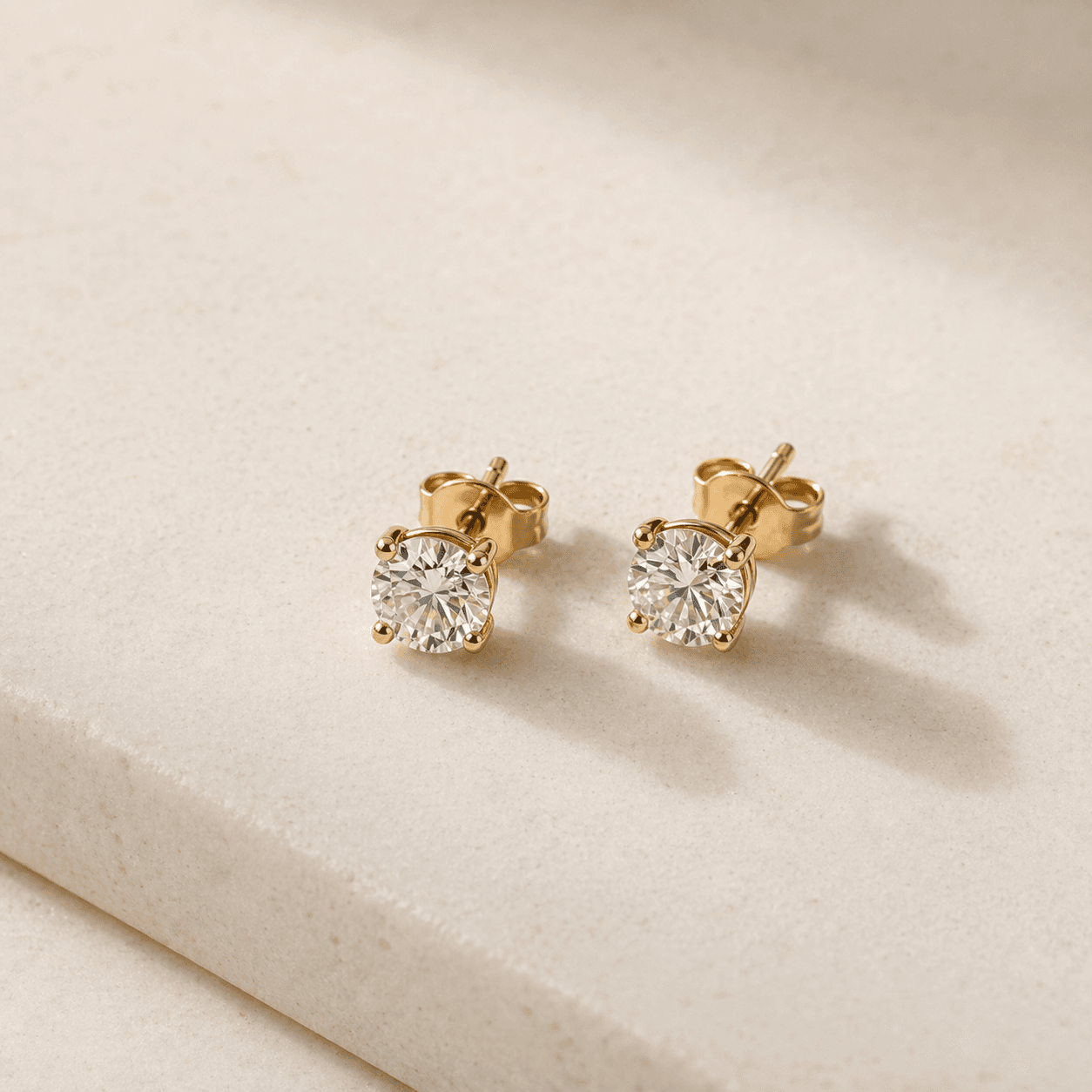 Moissanite stud earrings on warm ivory background