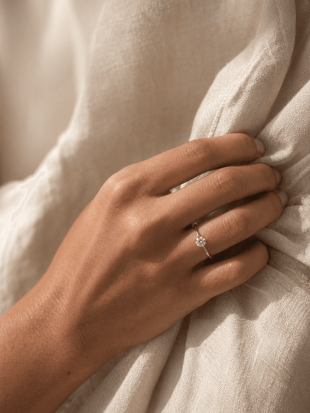 Solitaire moissanite ring worn with ivory linen